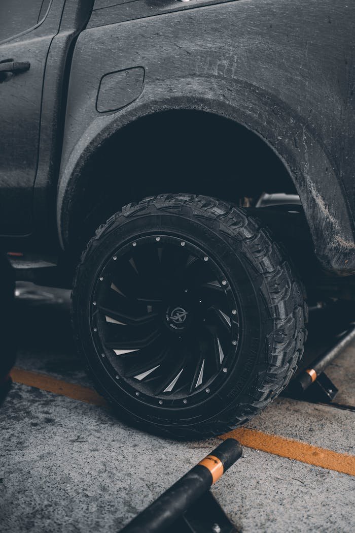Detailed close-up of a muddy truck tire, capturing rugged textures and urban setting.