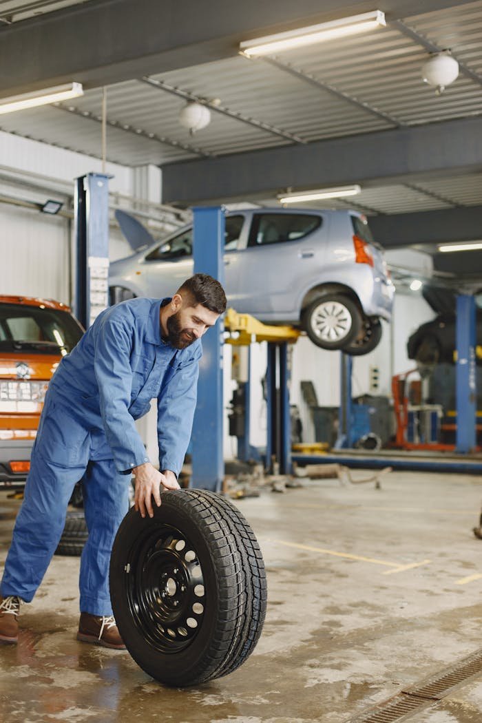 Mechanic handling a tire in a busy automotive repair workshop.